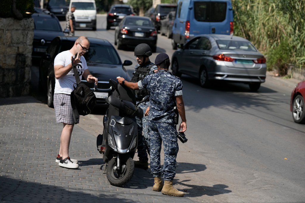 Lebanese soldiers check a driver motorcycle document as investigators collect forensic evidence on a road leading to the U.S. Embassy in Aukar, a northern suburb of Beirut, Lebanon, Wednesday, June 5, 2024. 