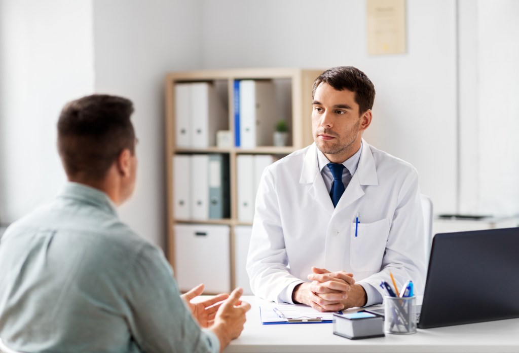 Doctor in white coat discussing healthcare with a male patient in a hospital setting