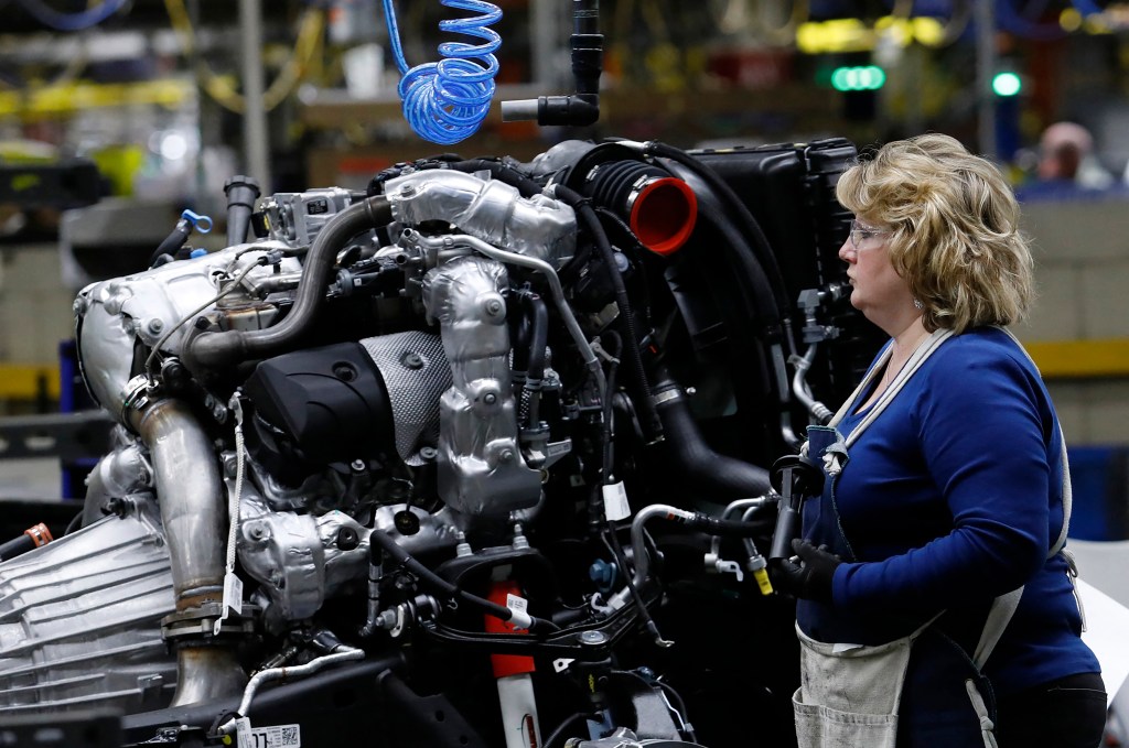 Line workers work on the chassis of full-size General Motors pickup trucks at the Flint Assembly plant 