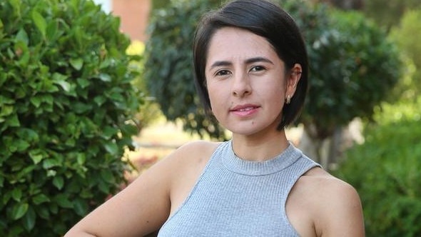 A woman with short dark hair wearing a grey tank top, representing one of the thousand women involved in a $25 million settlement against a cosmetic clinic