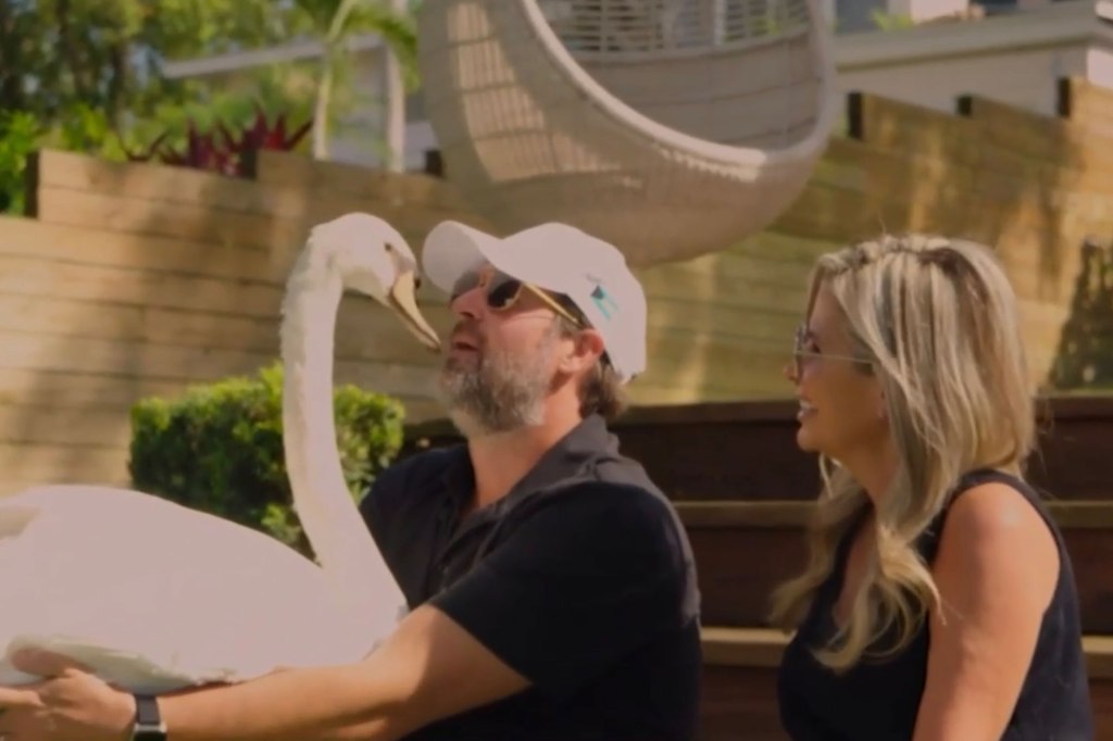 Andrew Marshall holds a swan while sitting next to his wife PJ Garcia-Marshall