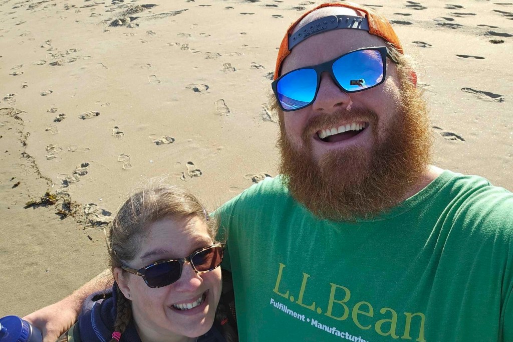 Patrick Acord with his wife Jamie, who sunk to her hips in quicksand on Popham Beach, Maine, taking a selfie with sand in background.