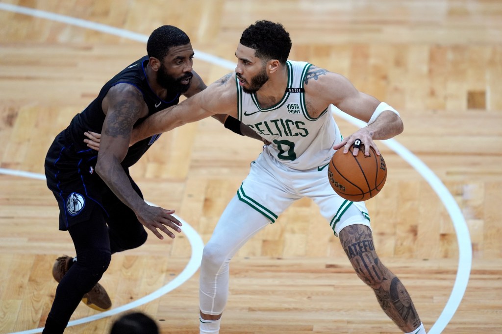 Boston Celtics forward Jayson Tatum, right, fends off Dallas Mavericks guard Kyrie Irving during the second half of Game 1 of basketball's NBA Finals on Thursday, June 6, 2024, in Boston.