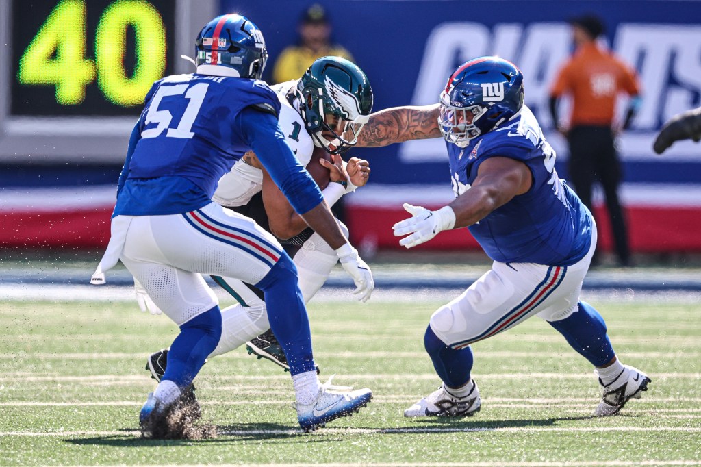 Azeez Ojulari (left) and Dexter Lawrence sack Eagles quarterback Jalen Hurts on Oct. 20, 2024 at MetLife Stadium.