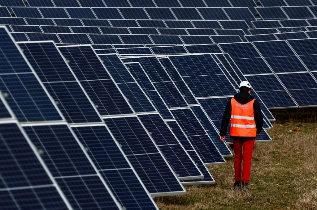 Engie employee walking past solar panels at a photovoltaic park in Marcoussis, near Paris, France