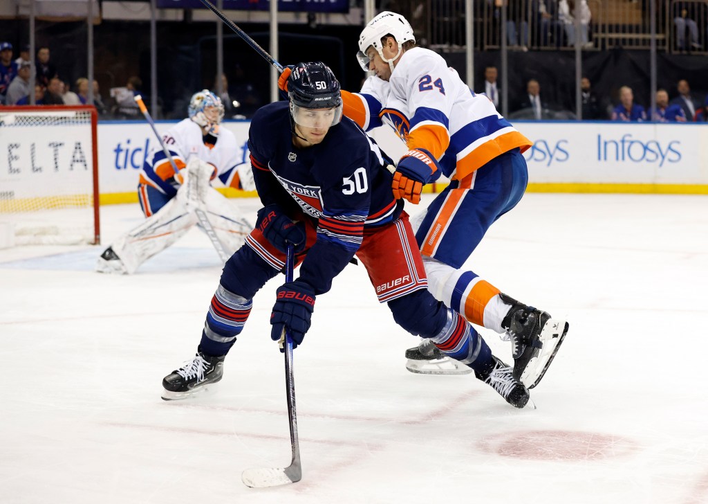 Rangers left wing Will Cuylle (C) tries to control a loose puck against New York Islanders defenseman Scott Mayfield (R) in the third period at Madison Square Garden in New York, USA, Sunday, November 03, 2024.