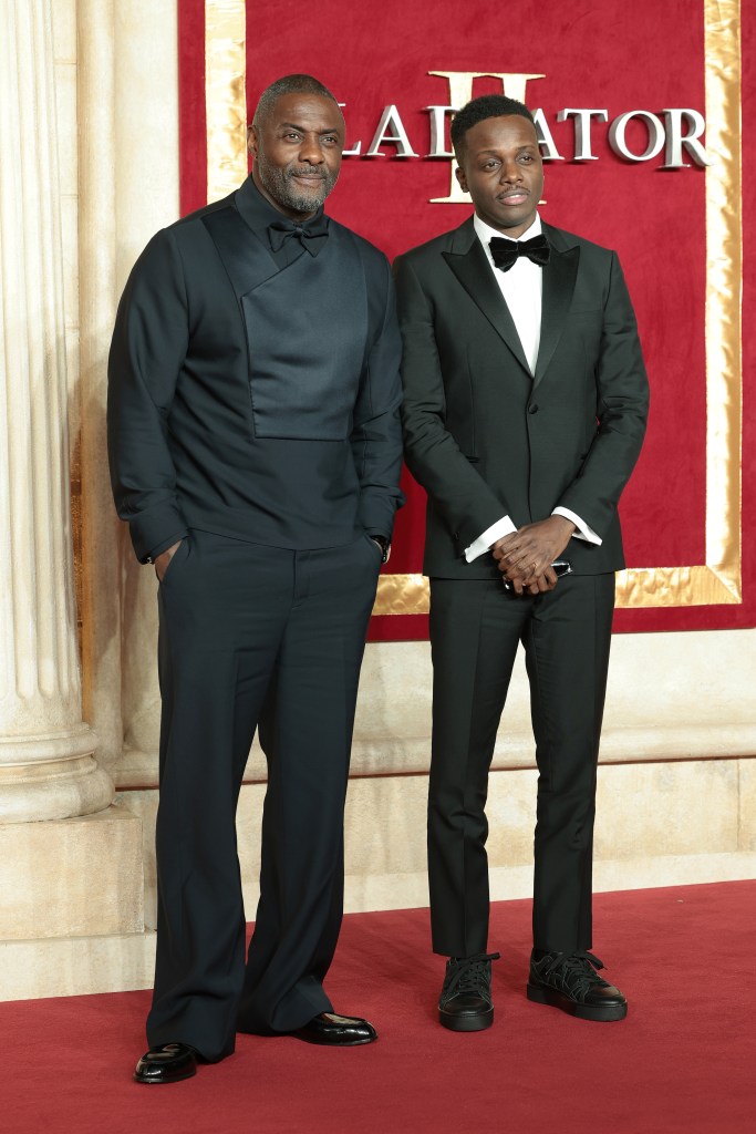 Idris Elba and Riaze Foster in black suits attending the 'Gladiator II' global premiere in London, standing in front of a red wall