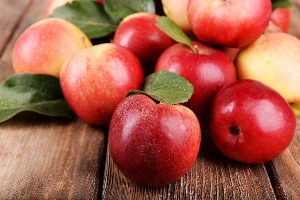 Group of ripe red apples on a wooden surface