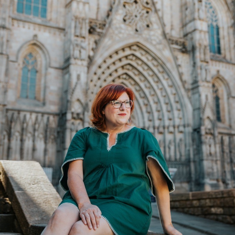 Jen Barnett, co-founder of Expatsi.com, sitting on a stone bench in front of a building