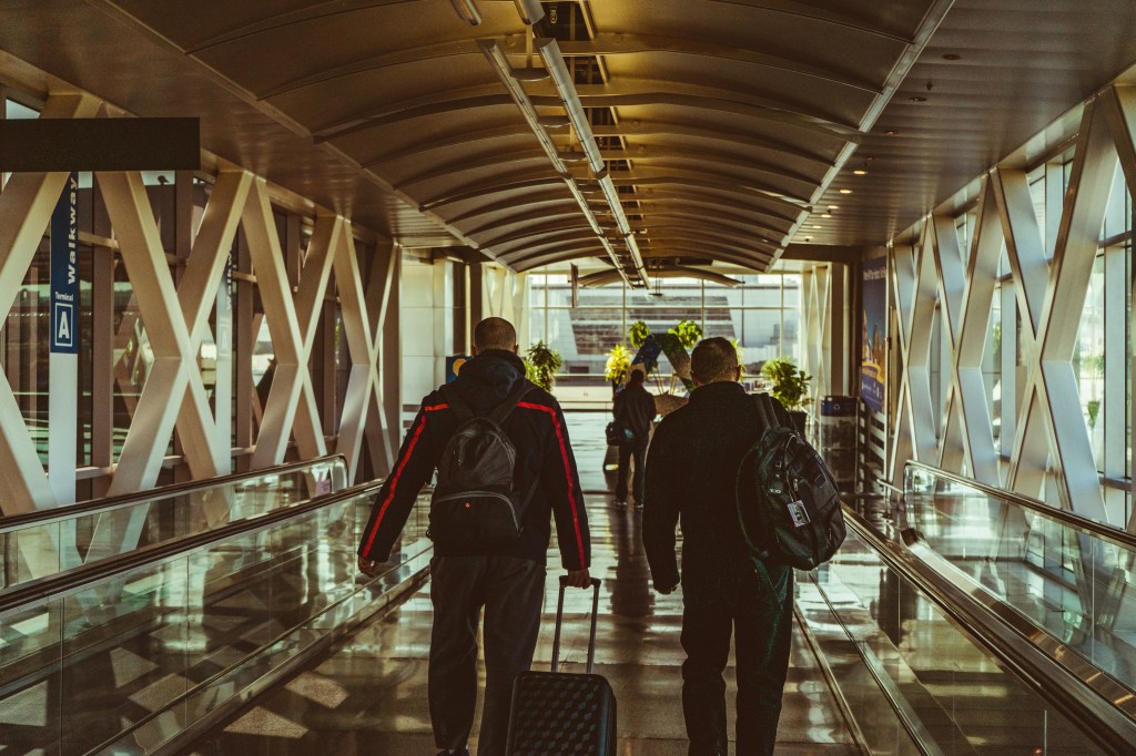 People walking down a walkway with luggage, reflecting the concept of travel disruption