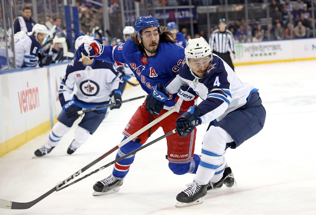 Mika Zibanejad #93 of the New York Rangers and Neal Pionk #4 of the Winnipeg Jets fight for position during the first period on Monday.
