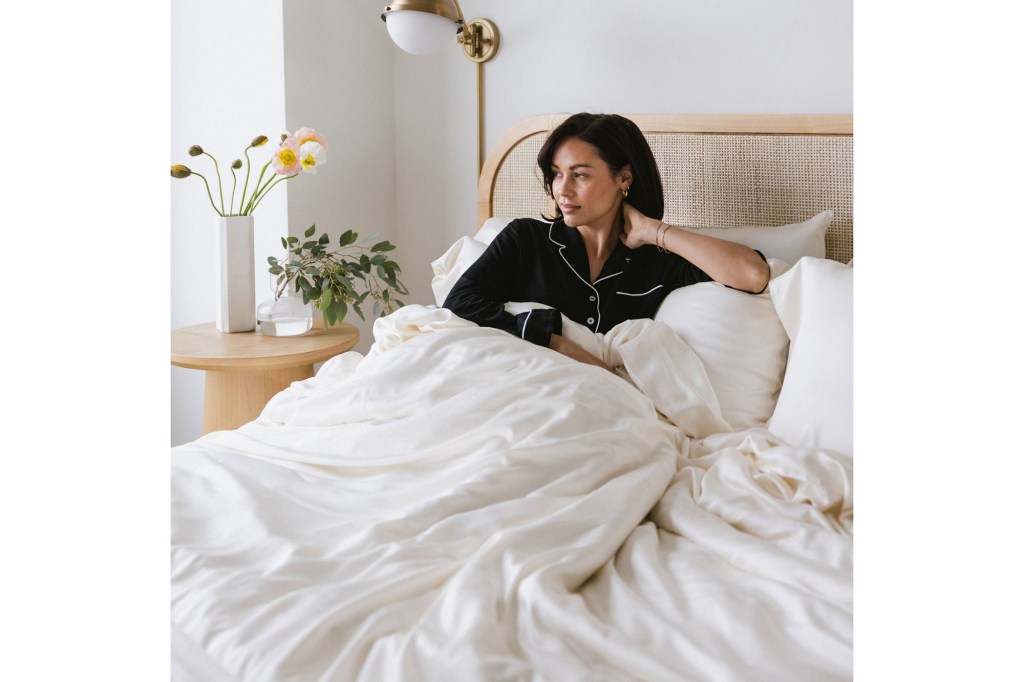 A woman sitting in a bed with Cozy Earth sheets