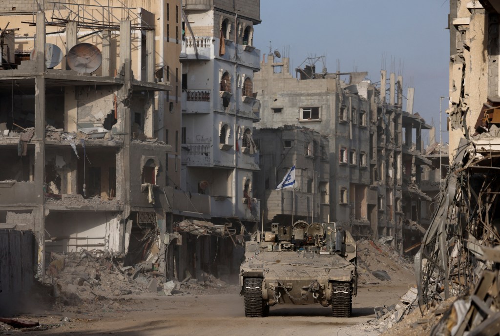 Armoured vehicle driving with damaged buildings in the background during the Israeli army's ground operation against Hamas in the Gaza Strip, September 2024