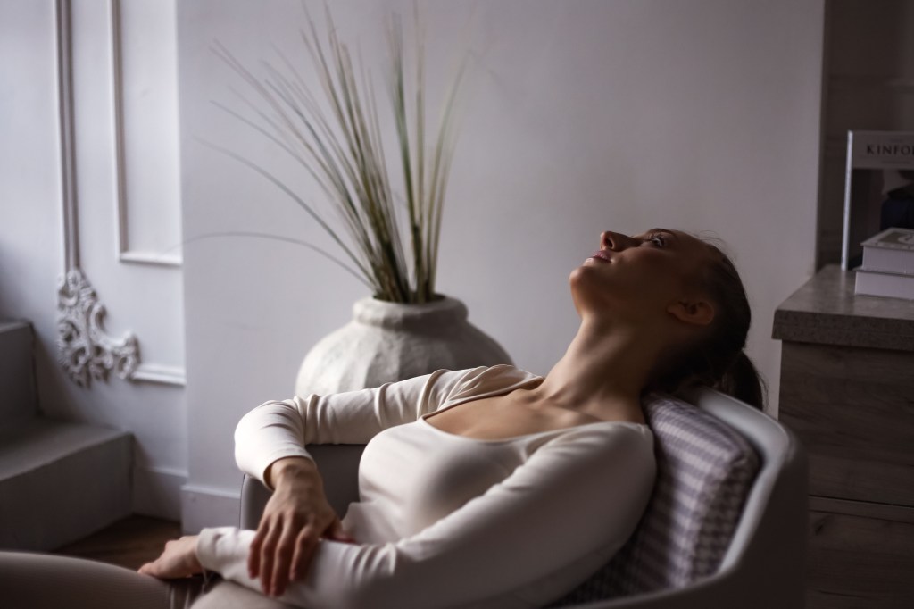 Depressed woman sitting alone in a shadowy room, indicating the concept of mental health, stress and depression