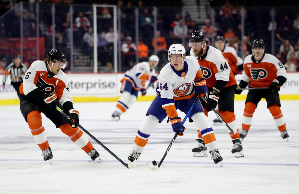 New York Islanders player Calum Ritchie #64 controlling the puck against Philadelphia Flyers players Travis Sanheim #6 and Nick Seeler #44.