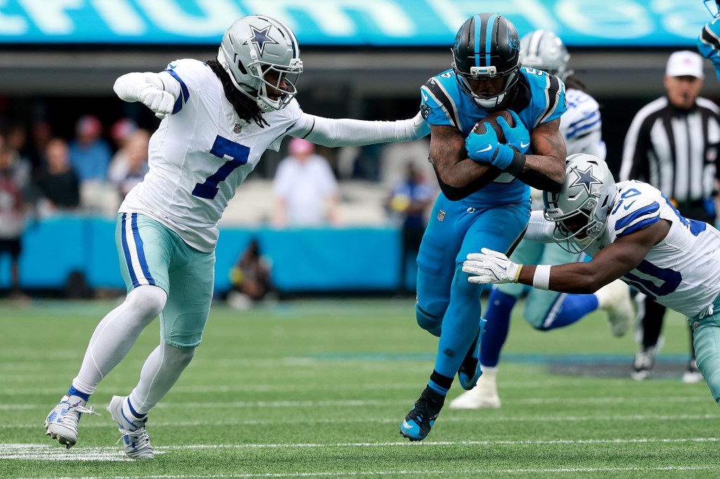 Carolina Panthers player Rico Dowdle #5 is tackled by Dallas Cowboys players Trevon Diggs #7 and Shemar James #50.
