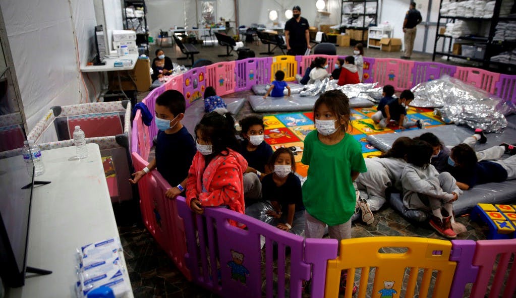 DONNA, TEXAS - MARCH 30: Young unaccompanied migrants, ages 3-9 watch TV inside a playpen at the Department of Homeland Security holding facility on March 30, 2021 in Donna, Texas. The Donna location is the main detention center for unaccompanied children coming across the U.S. border in the Rio Grande Valley. (Photo by