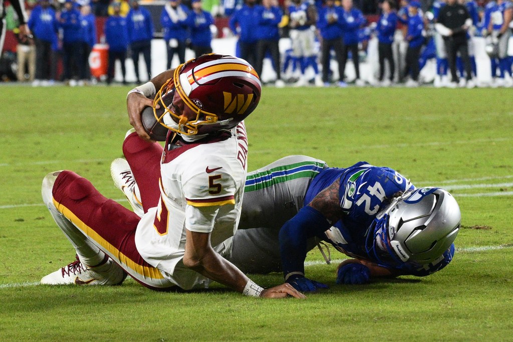 Washington Commanders quarterback Jayden Daniels (5) injures his arm as he is tackled by Seattle Seahawks linebacker Drake Thomas (42).