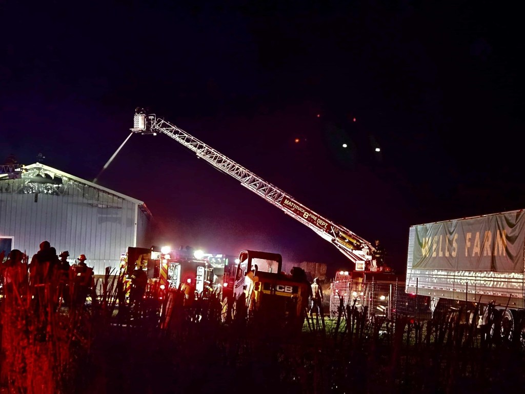 Firefighters extinguish a fire at Wells Farm at night.