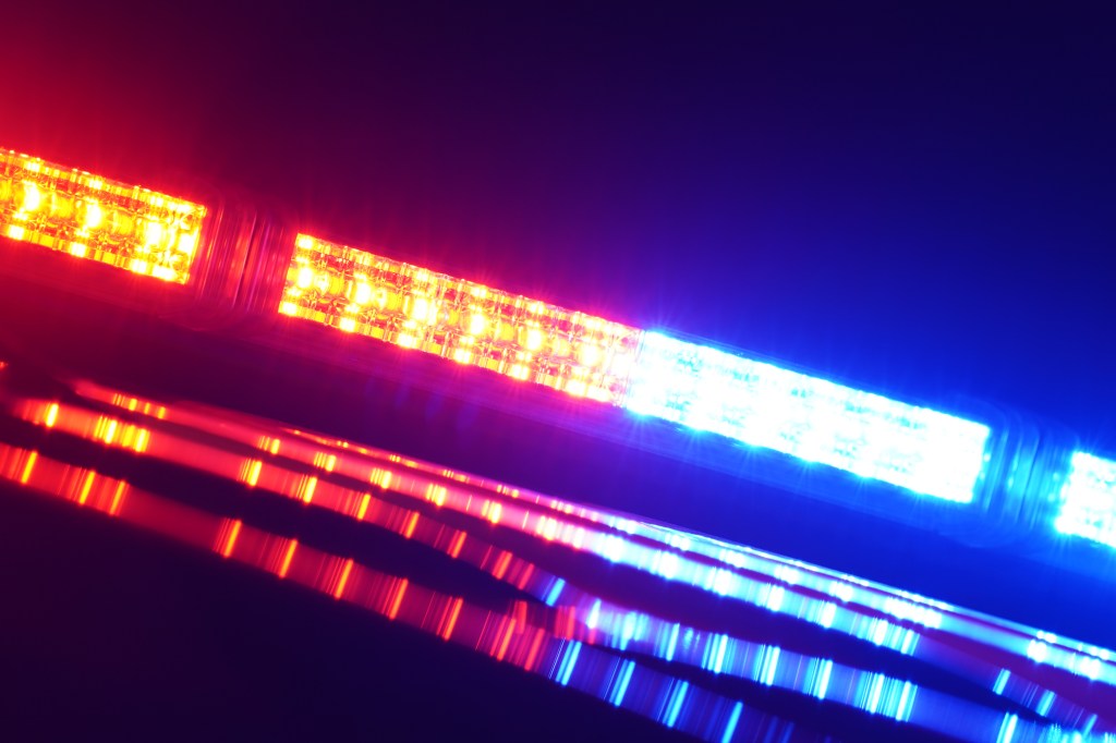 A close-up of a police car light bar, with red and blue emergency lights flashing.