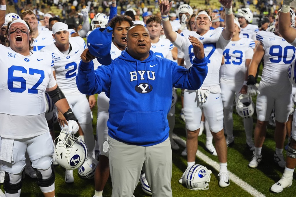 BYU football coach Kalani Sitake celebrates with his team on the field.