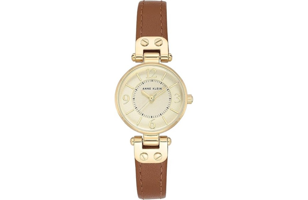 Anne Klein women's watch with a gold-colored case, a cream-colored dial with gold markings, and a brown leather strap.