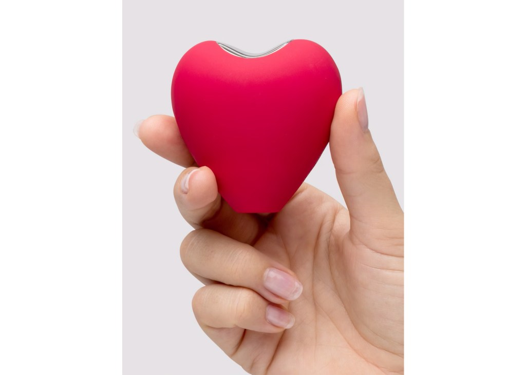 Hand holding a small, red, heart-shaped personal massager.