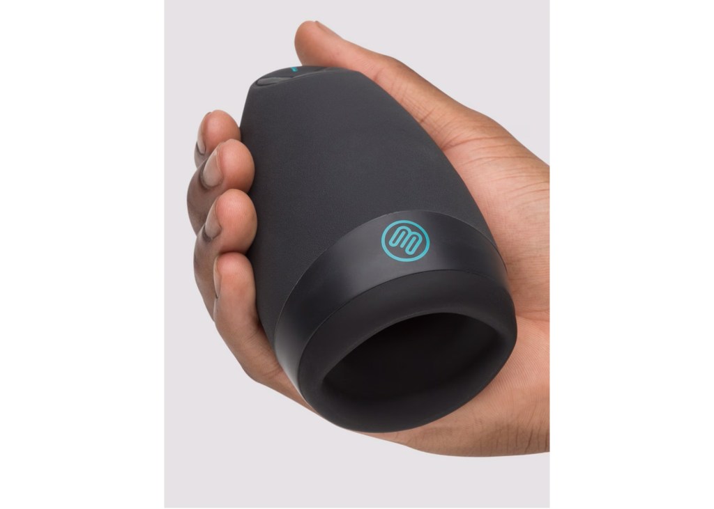 Hand holding a black male masturbator with an M-shaped logo in blue.