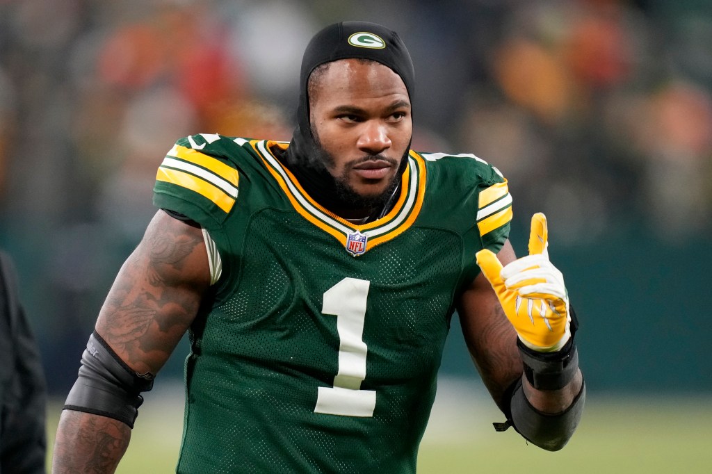 Micah Parsons in a Green Bay Packers jersey and black balaclava, giving a thumbs up.