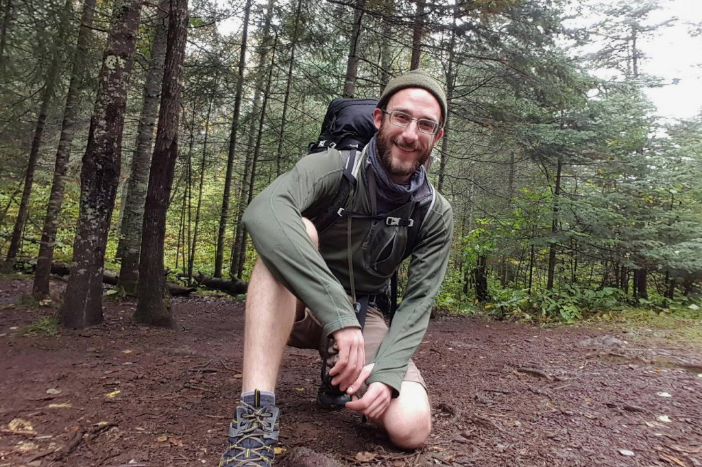 Alex J. Pretti crouching on a muddy trail in a forest.