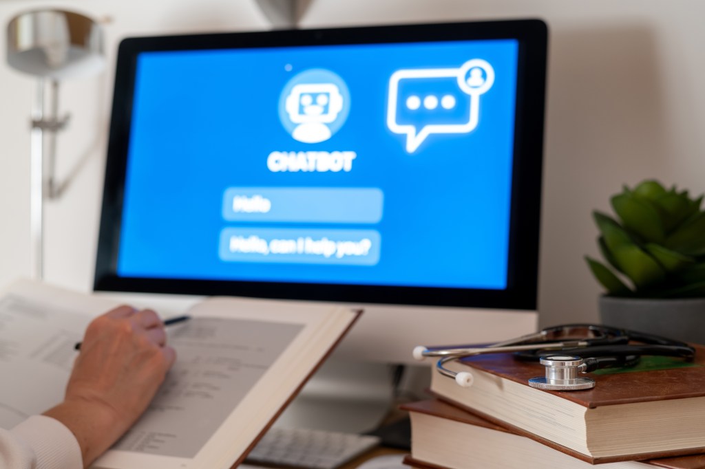 Medical student learning with an AI chatbot displayed on a computer screen, with medical books and a stethoscope on the desk.