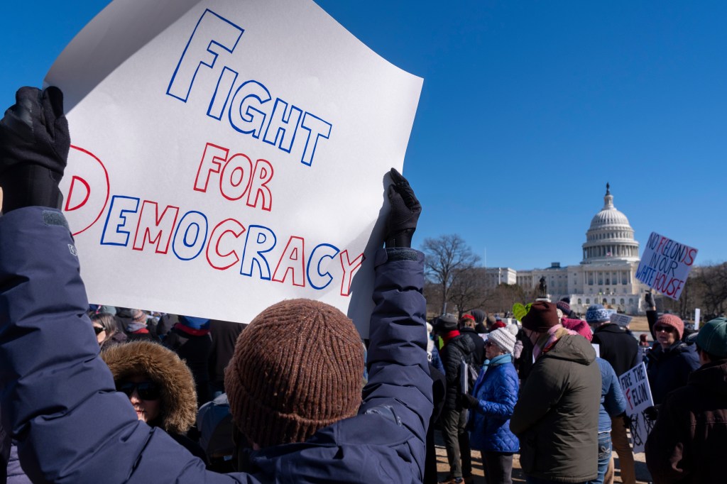 A protester holds a sign that reads "Fight For Democracy" in front of the US Capitol Building.