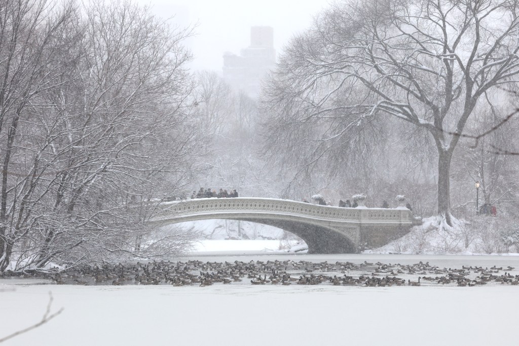 People walk across the Bow Bridge in a snow-covered Central Park in New York City on December 27, 2025.