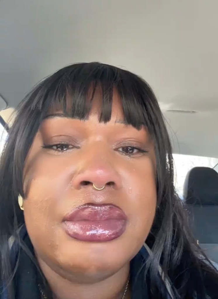 A woman with bangs and a nose ring crying.