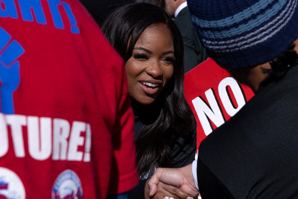 U.S. Representative Jasmine Crockett smiling and shaking hands with a constituent.