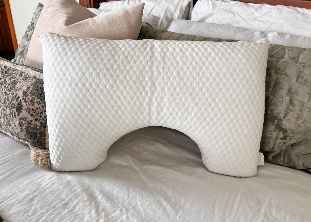 White hexagonal pattern pillow with a cutout for an arm on a bed.