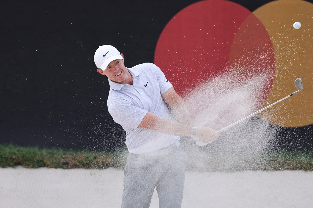 Rory McIlroy plays a shot from a bunker, sending sand flying, during the first round of the Arnold Palmer Invitational golf tournament.