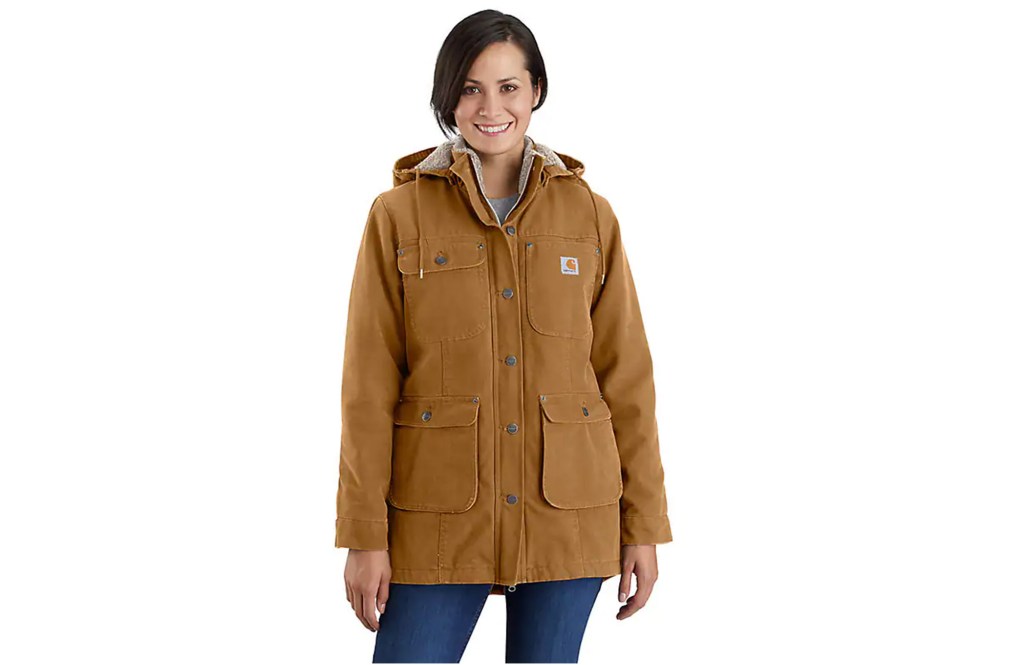 A woman in a brown rain jacket, standing by a car