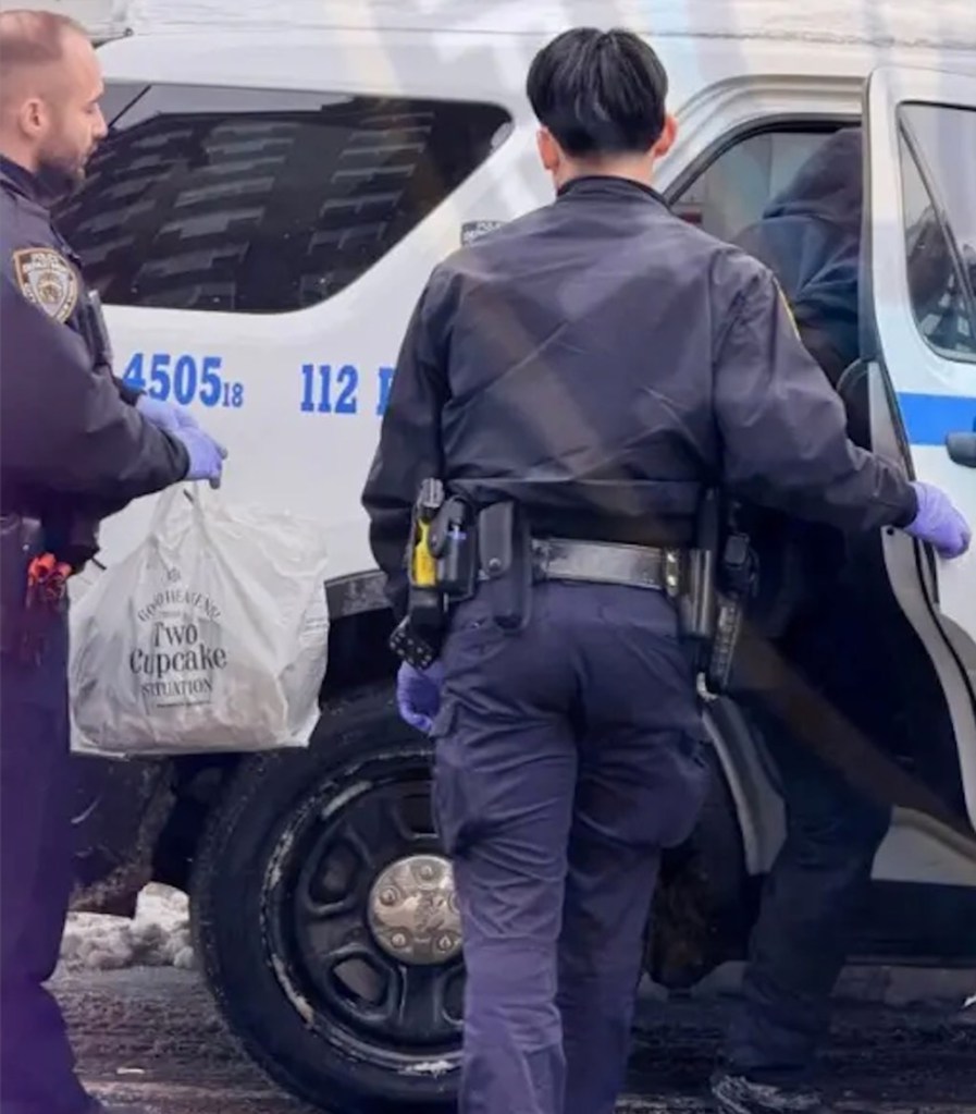 Two police officers next to a police vehicle, one holding a bag labeled "Two Cupcake Situation."