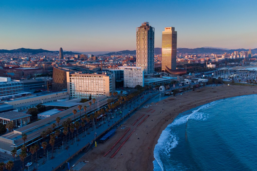 Aerial view of Barceloneta beach with buildings and city in the background.