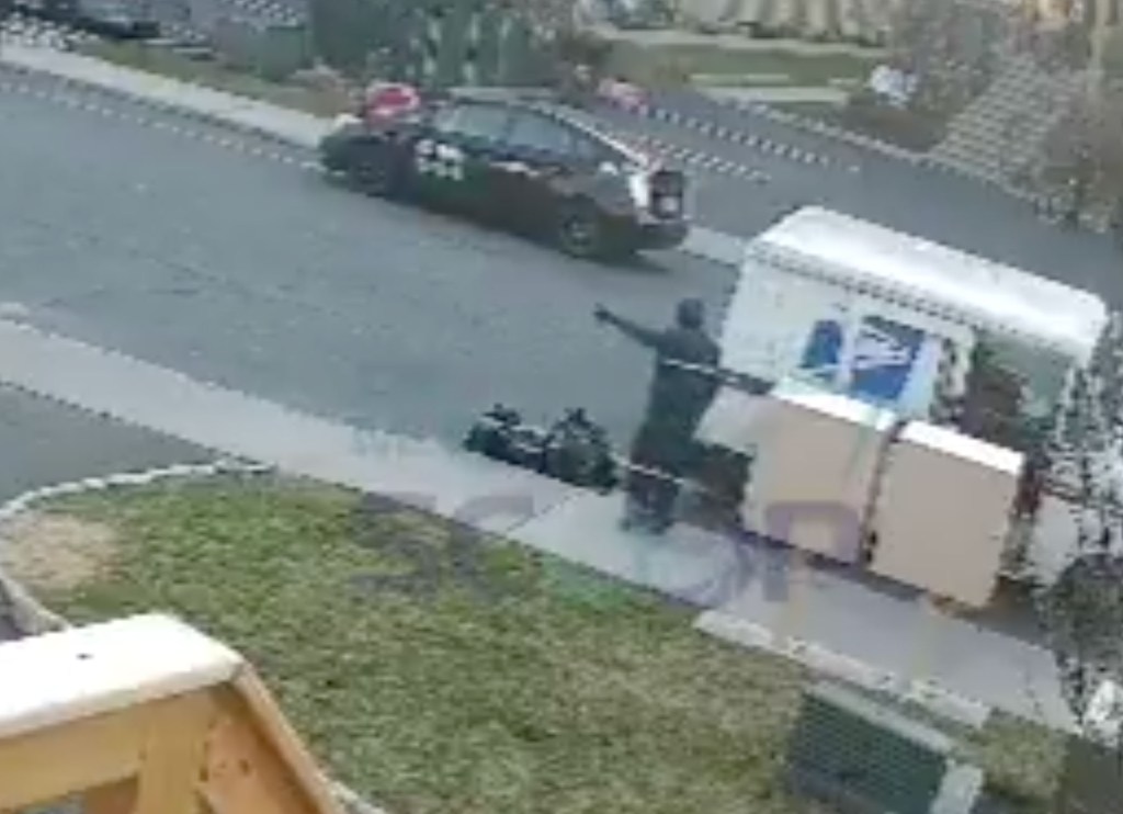 Overhead view of a postal worker pushing a child away from the postal truck on a residential street.