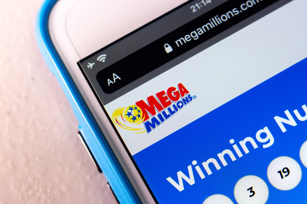 Closeup of the Mega Millions logo on a smartphone screen showing winning numbers.