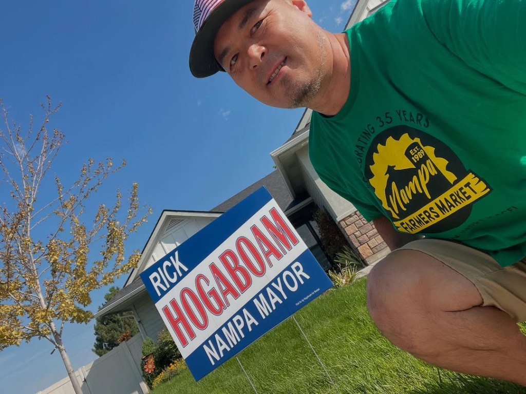 Rick Hogaboam posing next to a campaign sign for "Rick Hogaboam Nampa Mayor."