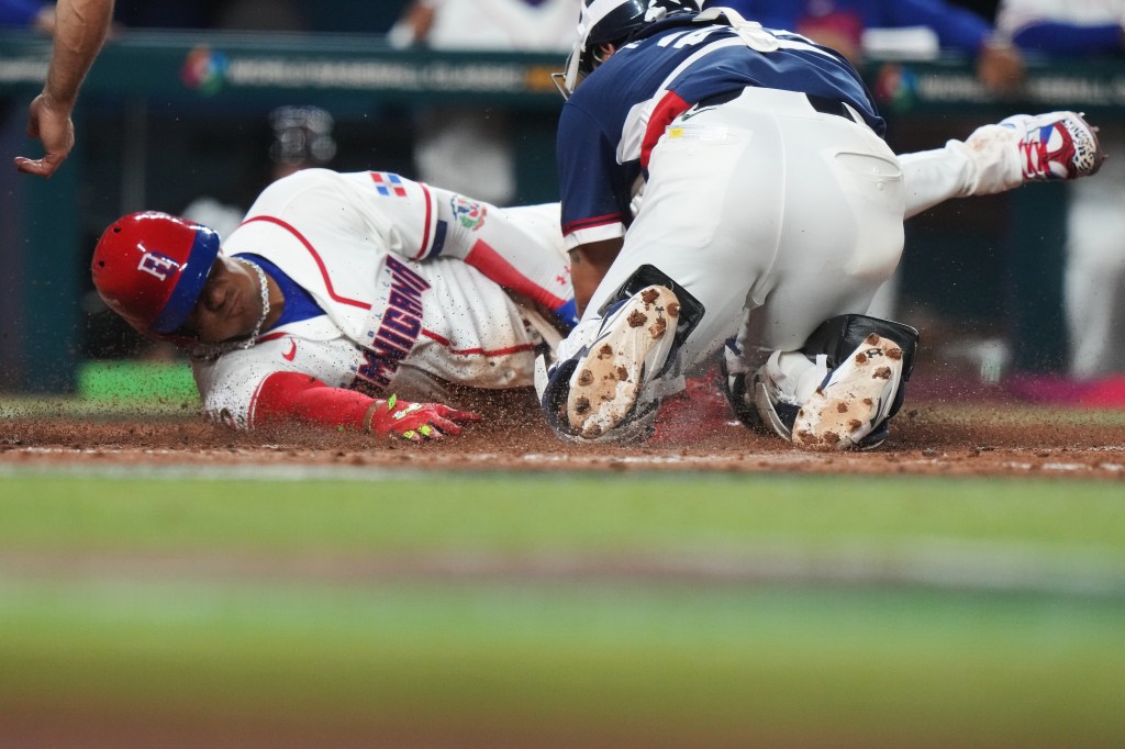 Juan Soto slides across home plate to score, while the South Korea catcher is on his knees behind him.