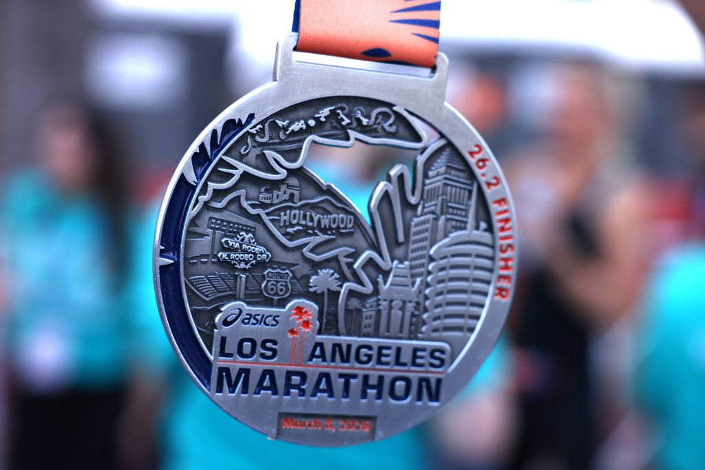 Close-up of a silver Los Angeles Marathon medal with "26.2 Finisher" engraved.