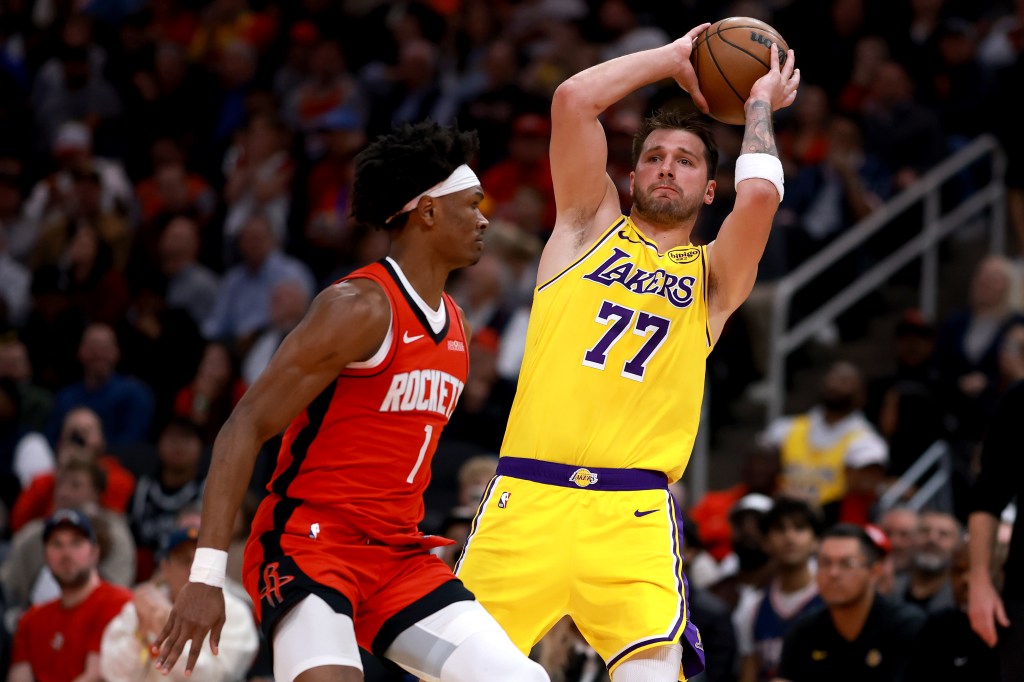 Luka Doncic (77) of the Los Angeles Lakers preparing to pass the ball while Amen Thompson (1) of the Houston Rockets defends him.