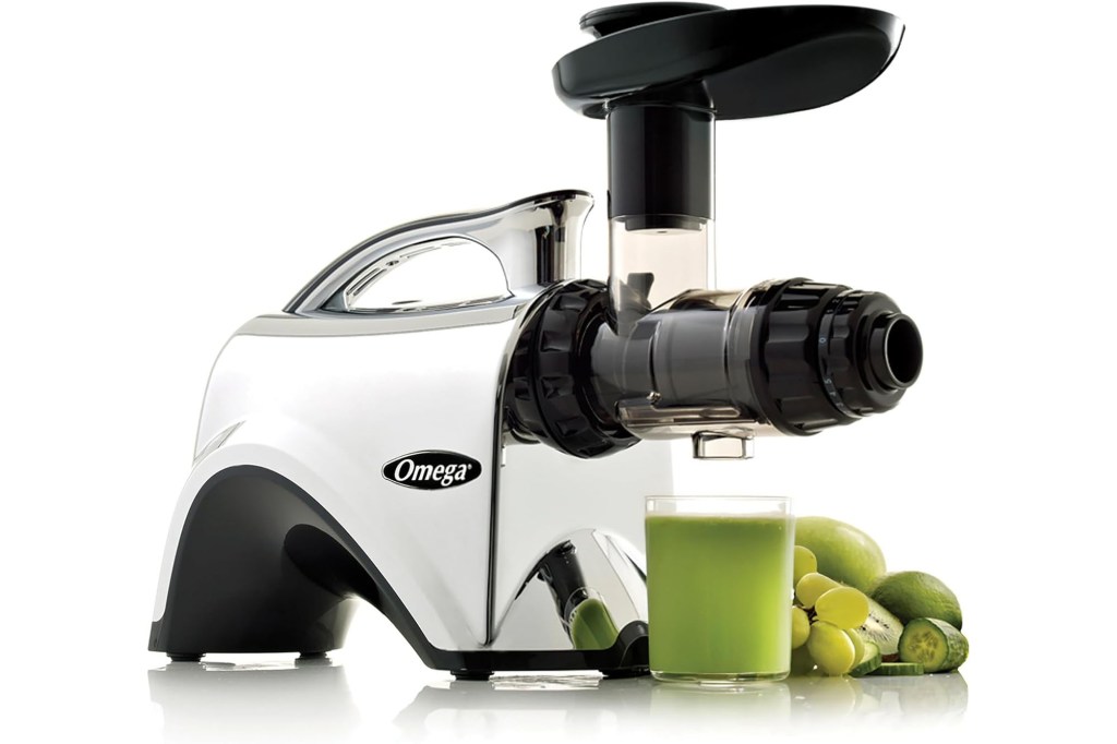 Omega juicer making green juice with fresh fruit and vegetables.