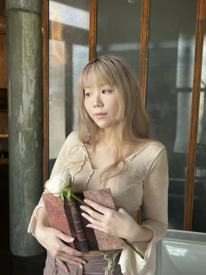 Kamonnan Thiamphanit holding a book and a white rose.