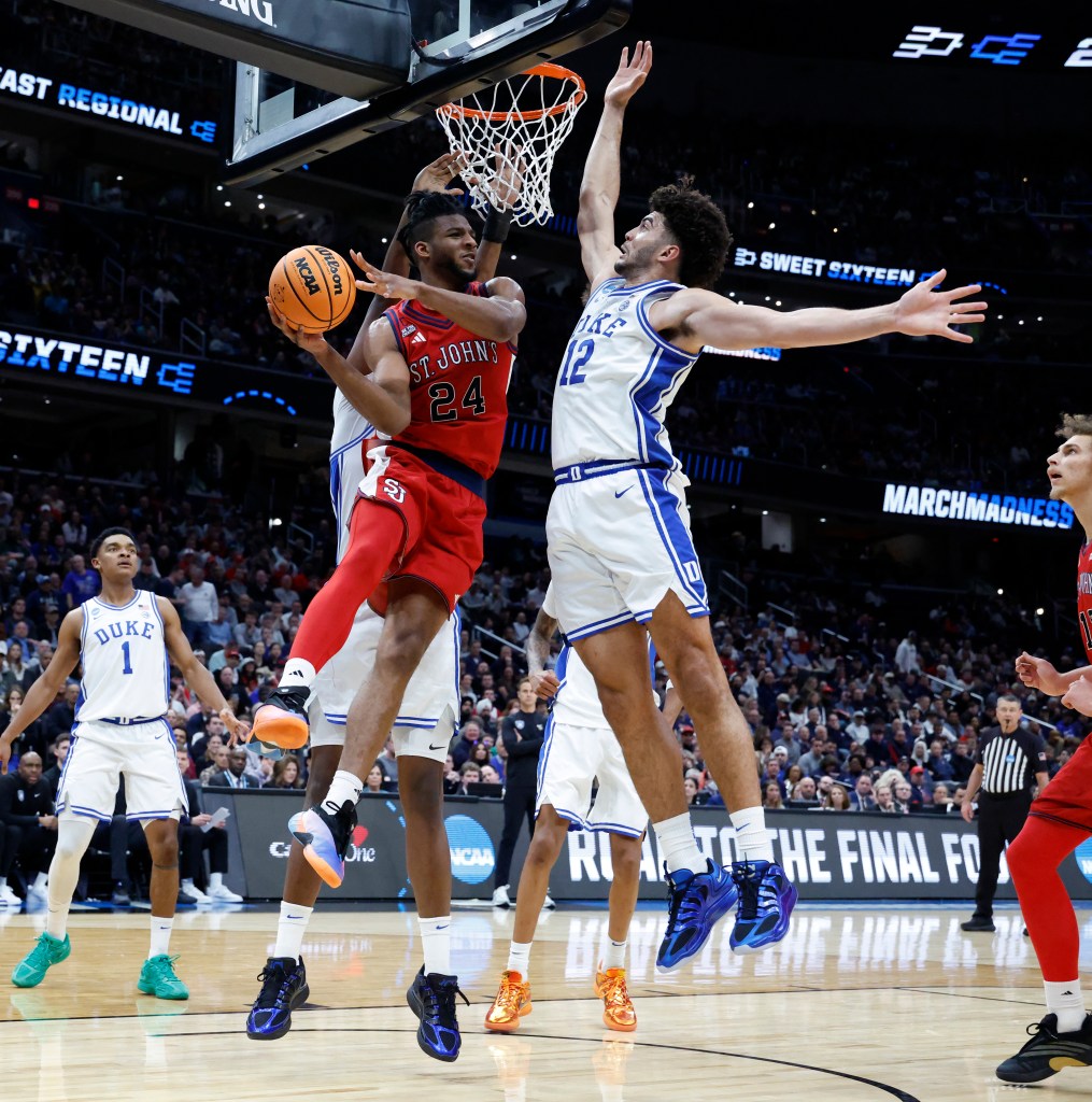 St. John's player Zuby Ejiofor attempts a shot while being defended by a Duke player during the NCAA Sweet Sixteen tournament.