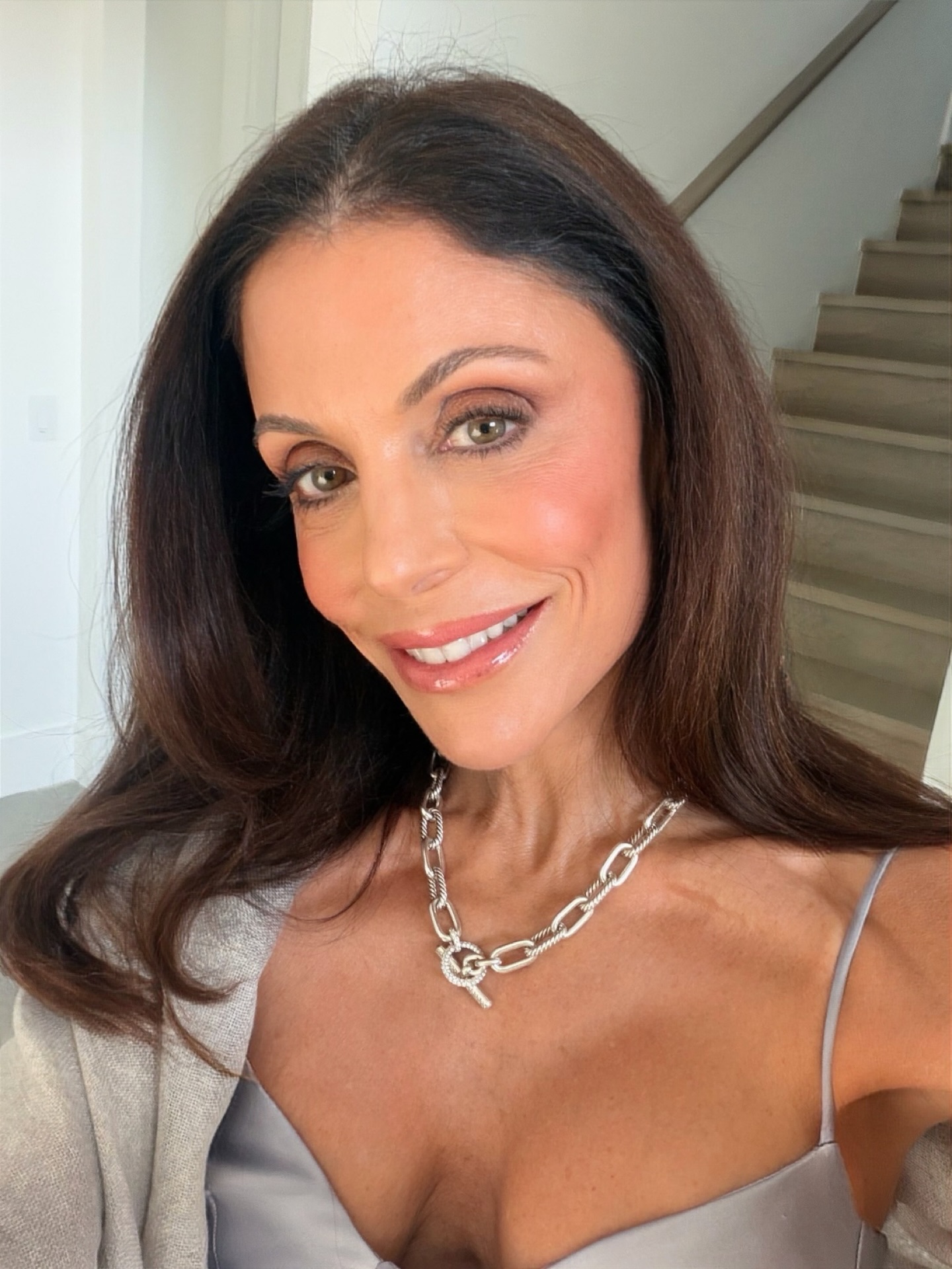 Bethenny Frankel smiling, wearing a silver chain necklace and a light blue top.
